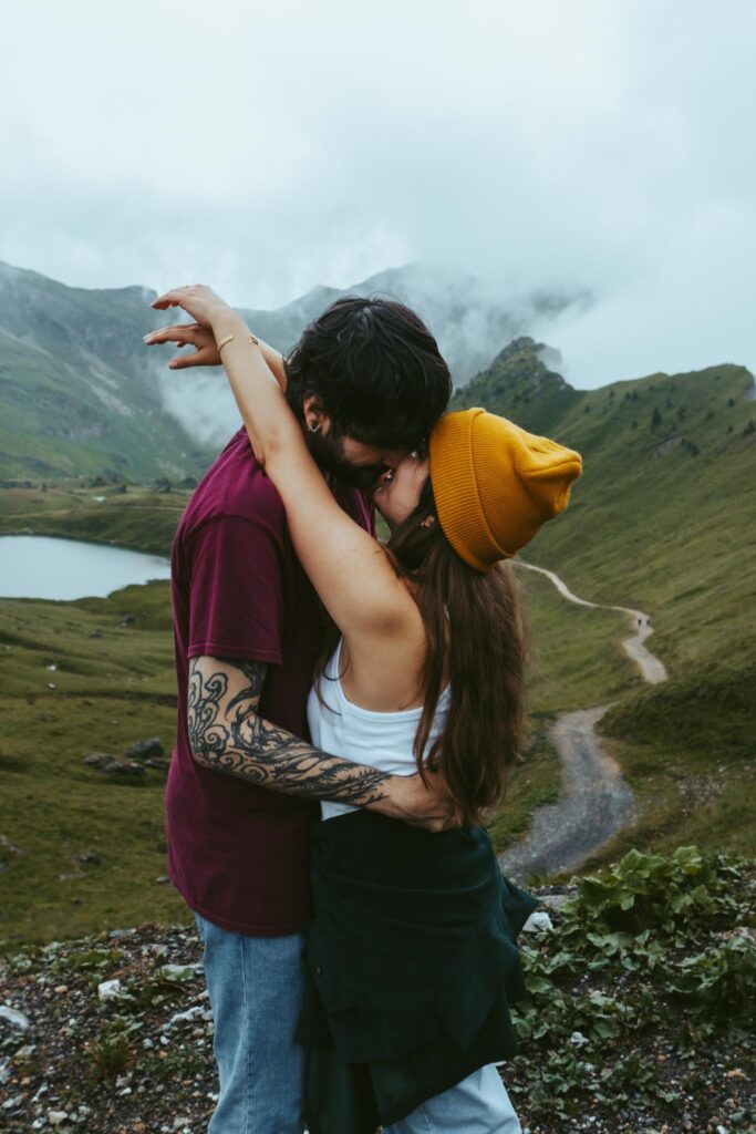 A couple holds each other during their couples session in Switzerland. The girl holds her arms around her boyfriend's neck as he has his hands on her waist and is leaning in to kiss