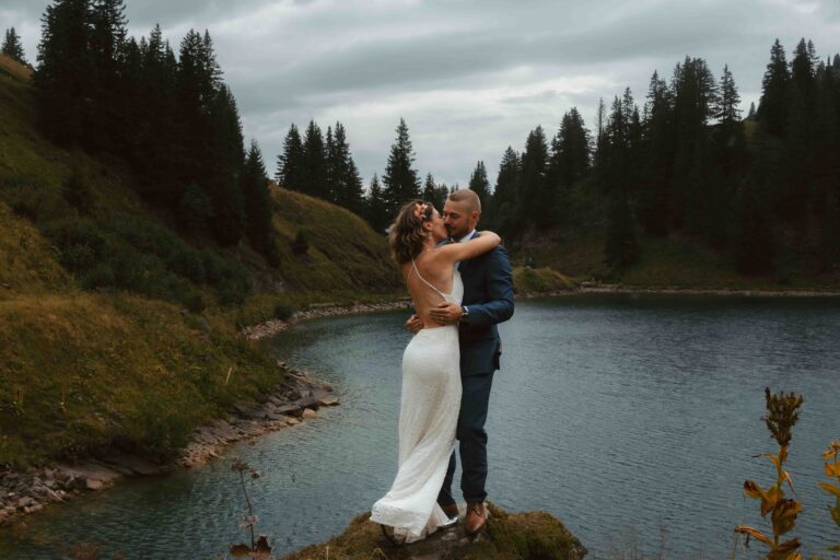 A couple hugs on a cliff in front of a swiss mountain lake during their elopement in Switzerland